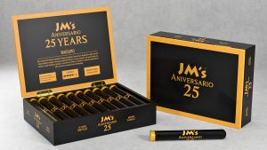 Open and closed boxes of JM’s Aniversario 25 Years Maduro cigars displayed with black cigar tubos, showing the anniversary branding on a neutral background.