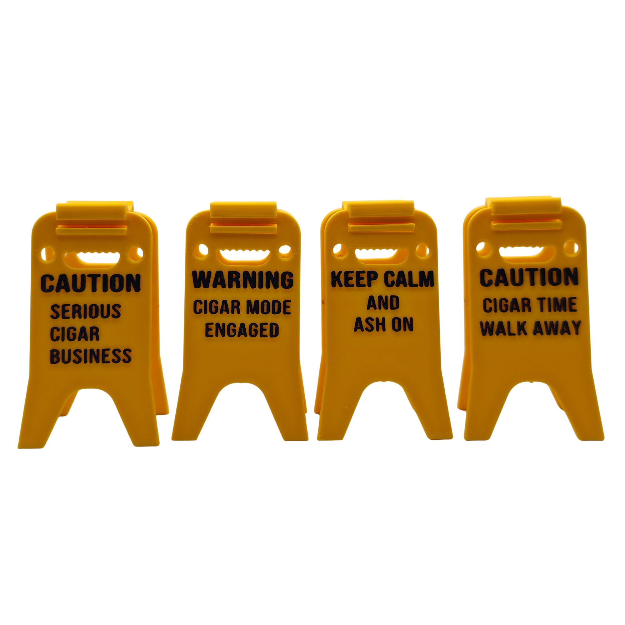 Bright yellow 3D printed cigar holder styled like a classic wet floor caution sign, printed with humorous cigar-related phrases in black text. The foldable design allows the sign to stand upright and serve as a portable cigar rest that keeps cigars elevated and off tables.