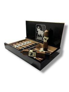 Open black cigar box displaying Juárez cigars, with one short, thick cigar standing upright and others resting inside the box. The box lid features the Juárez bull logo, and the cigars have black and gold bands.