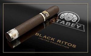 Single dark-wrapped Atabey cigar resting on a black reflective surface, with the Atabey logo and the words “Black Ritos – Limited Production” displayed beside it in gold lettering.