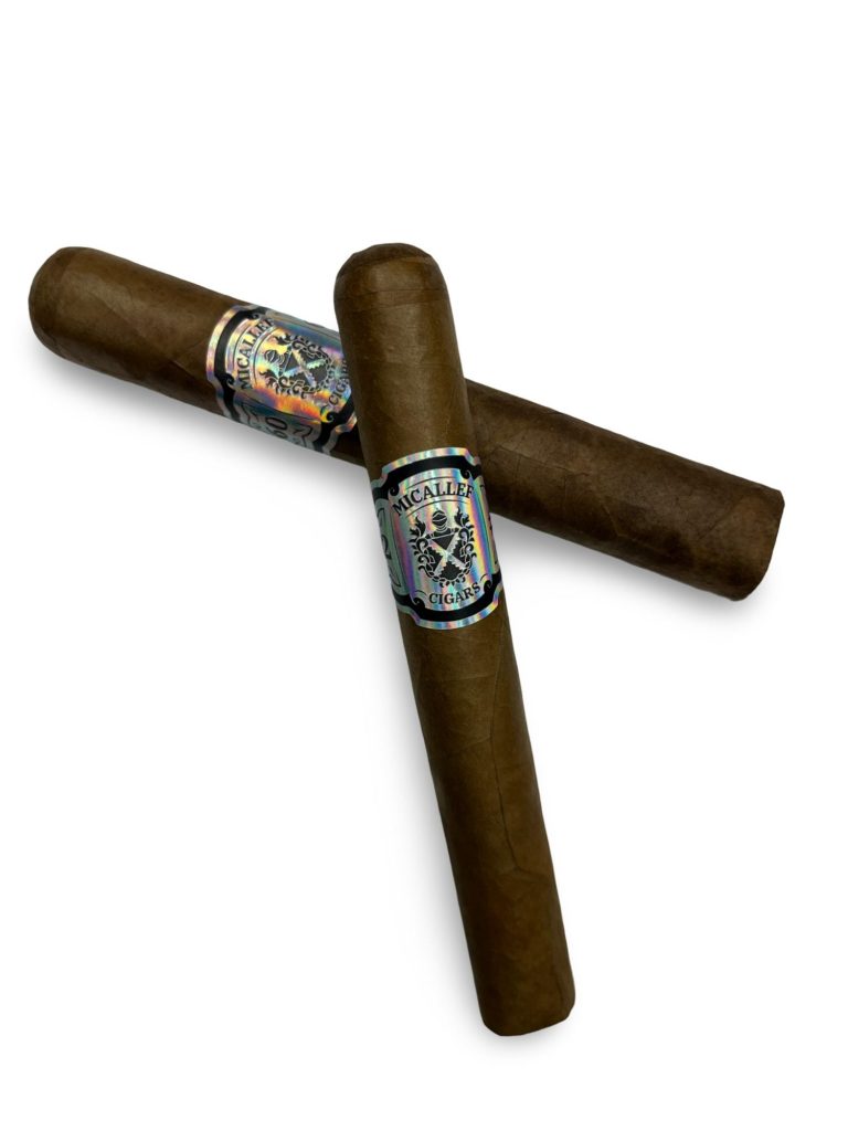 Two cigars, one laying on top of the other. Both have silver cigar bands on them.